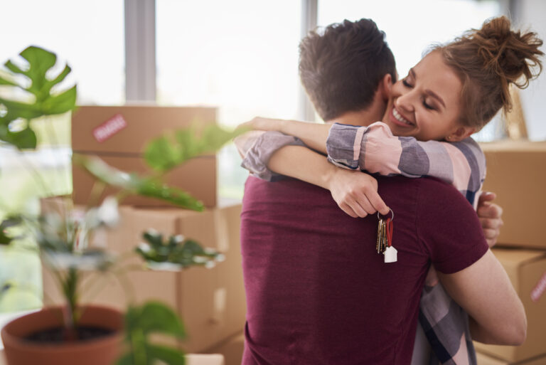 Pareja feliz abrazándose con llaves en la mano tras recibir su nuevo departamento gracias a FOGAES