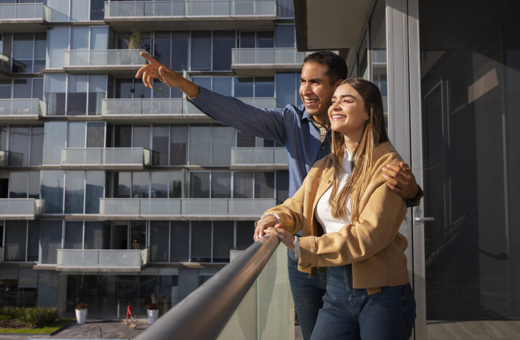 Pareja feliz observando su nuevo condominio desde el balcón