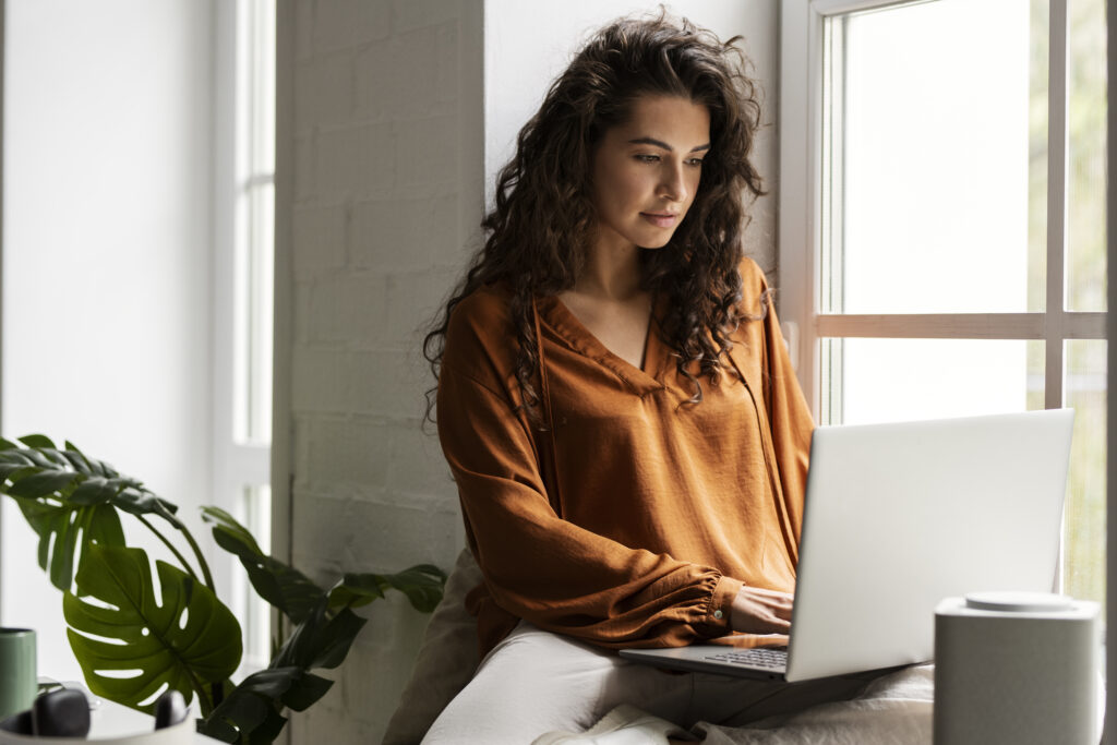Mujer joven revisando información sobre el FOGAES en su computador desde casa