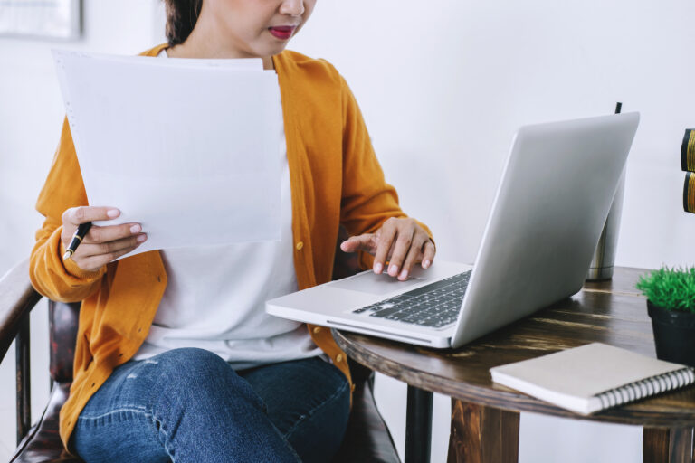 Mujer revisando certificado de subsidio habitacional y usando su computador para avanzar en la compra de vivienda
