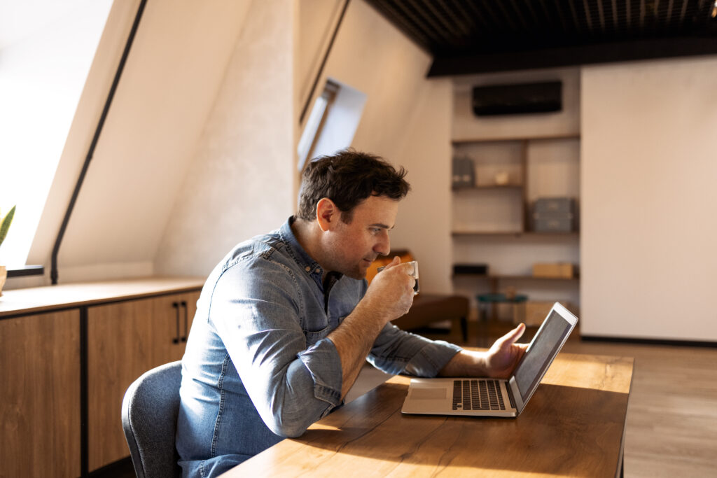 Hombre revisando su informe Dicom en el computador mientras toma café