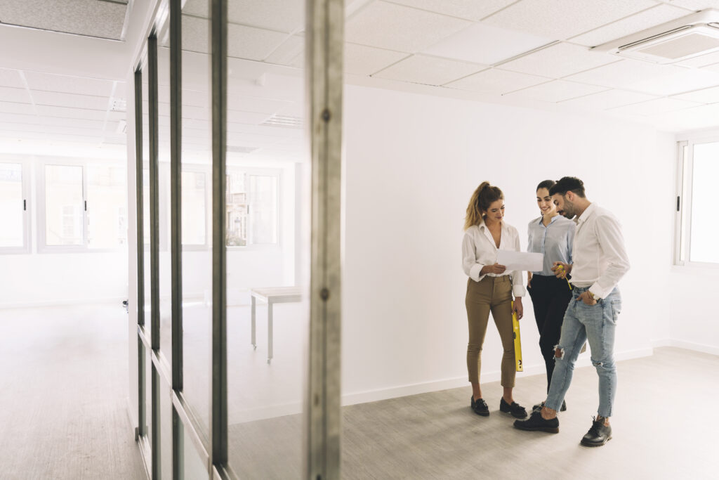 Equipo de profesionales revisando planos en un departamento vacío para inversión