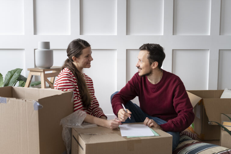 Pareja joven planificando su mudanza mientras organiza cajas en su nuevo hogar.