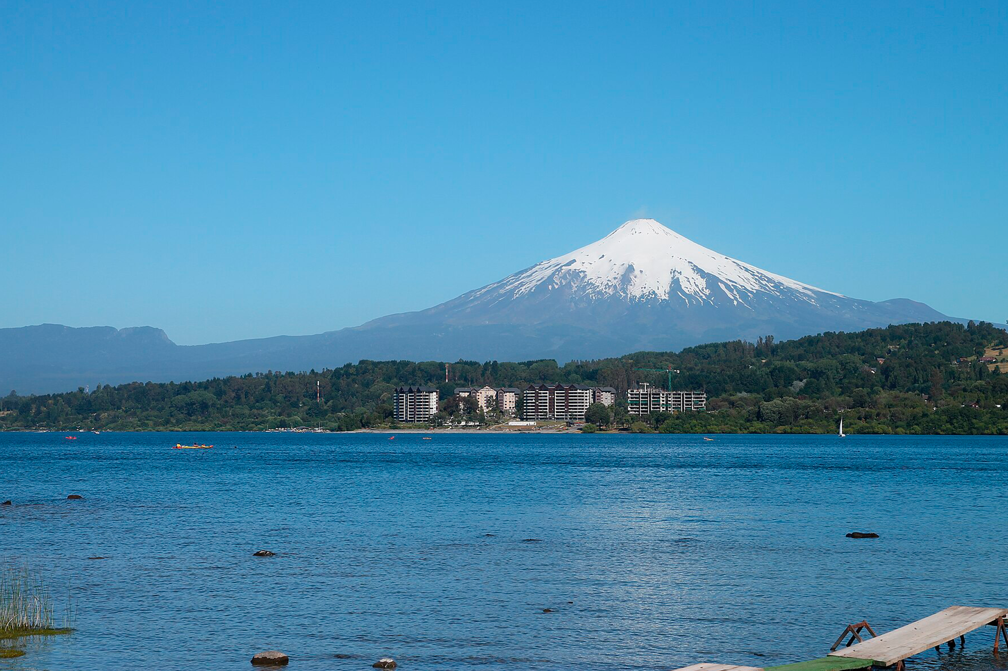 Vista del lago Villarrica con el volcán nevado al fondo y proyectos inmobiliarios en primera línea